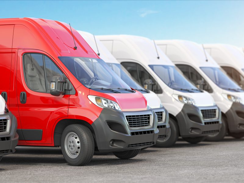 Red delivery van in a row of white vans. Best express delivery and shipemt service concept.